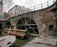 843968 Gezicht op de restauratiewerkzaamheden aan de Bakkerbrug over de Oudegracht te Utrecht, vanaf de werf aan de ...